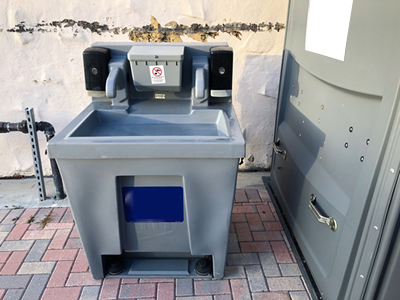 portable hand washing station next to a porta potty