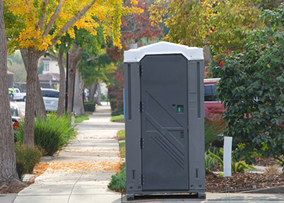 porta potty on the side walk with trees
